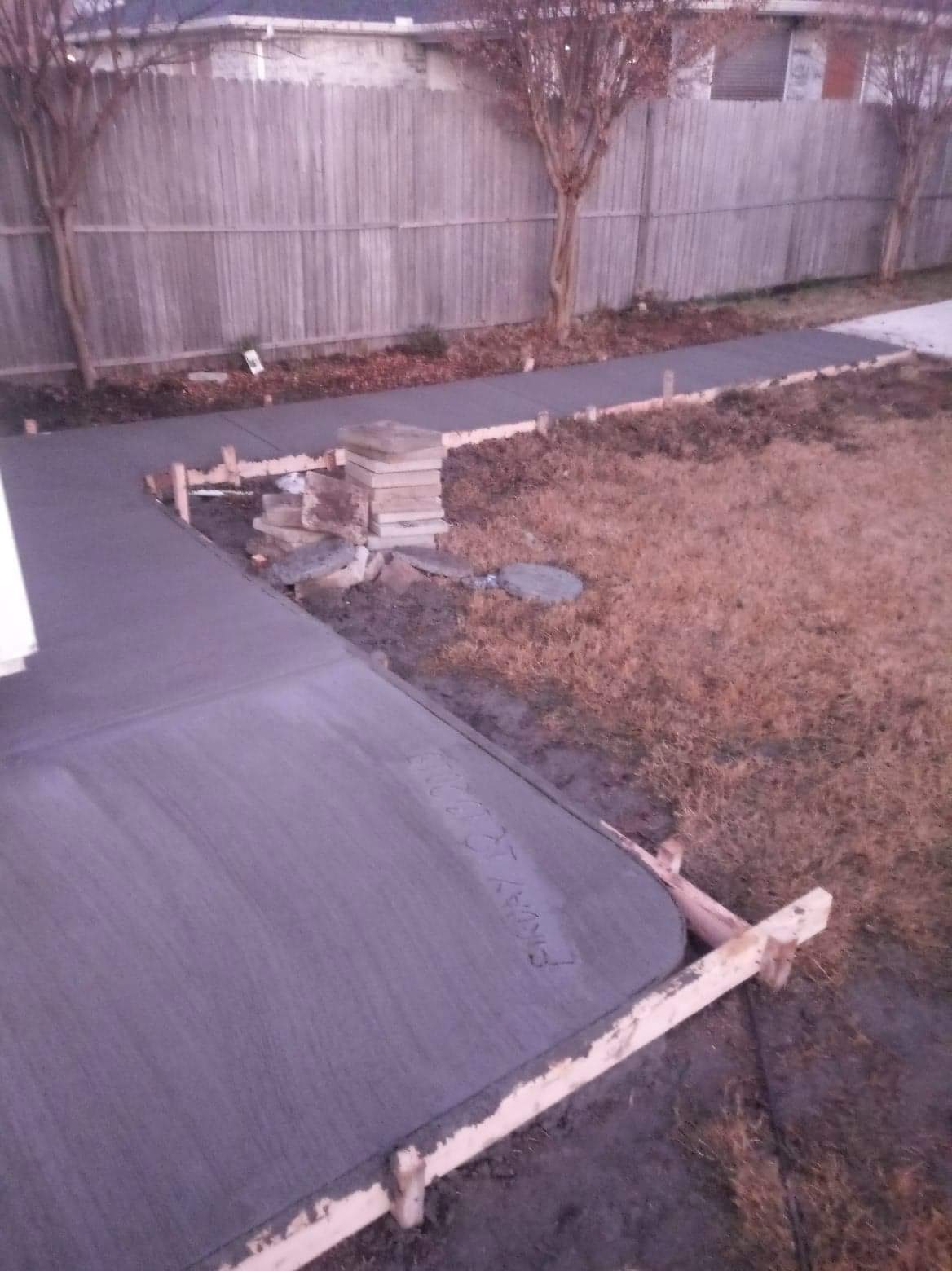 Fresh concrete walkway wrapping around a backyard