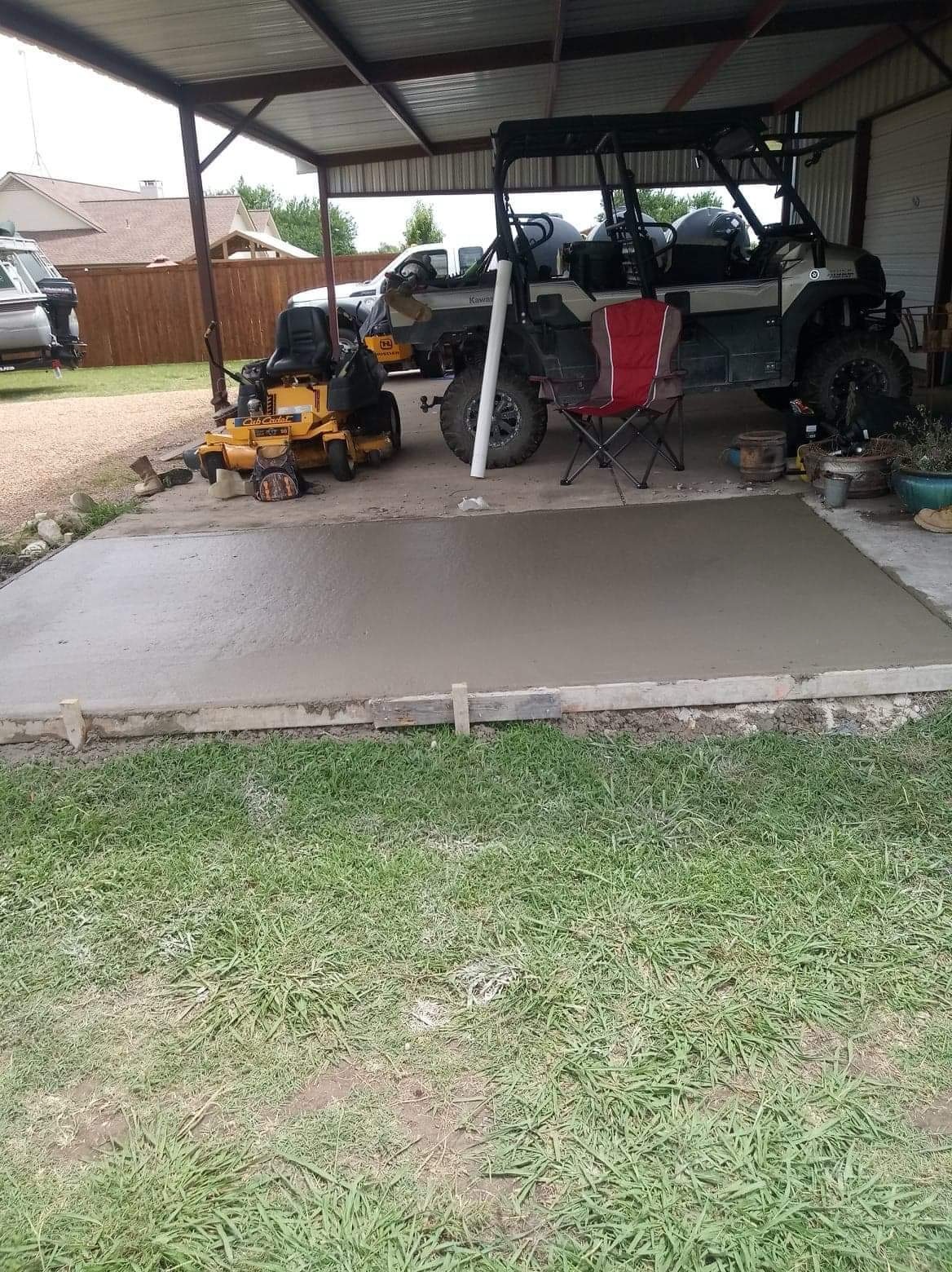Fresh concrete extension beneath a metal carport